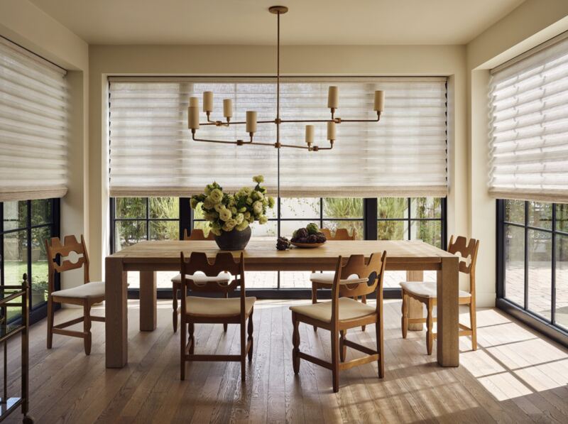 A dining room with soft, light-filtering Hunter Douglas shades across wide windows